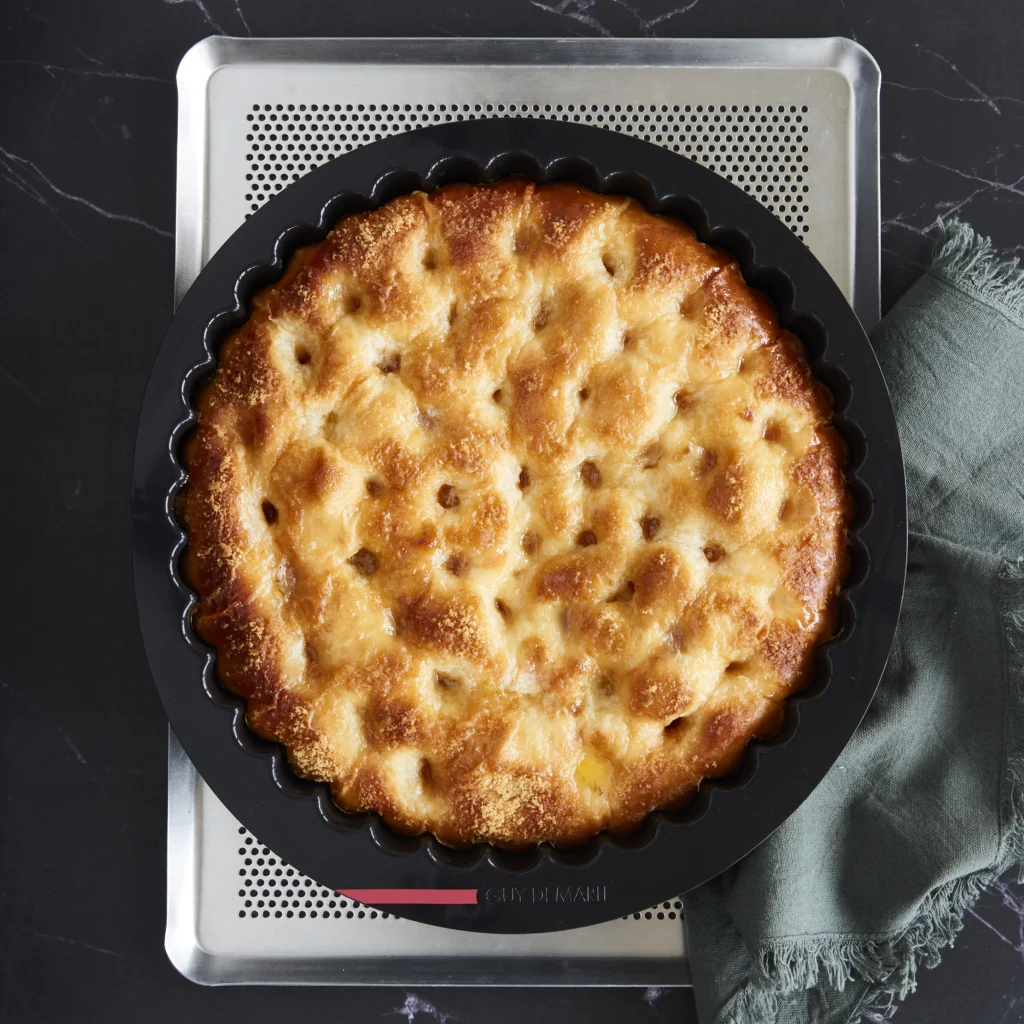 Overhead view of golden baked bread in a black Guy Demarle fluted silicone mold on a perforated baking sheet.